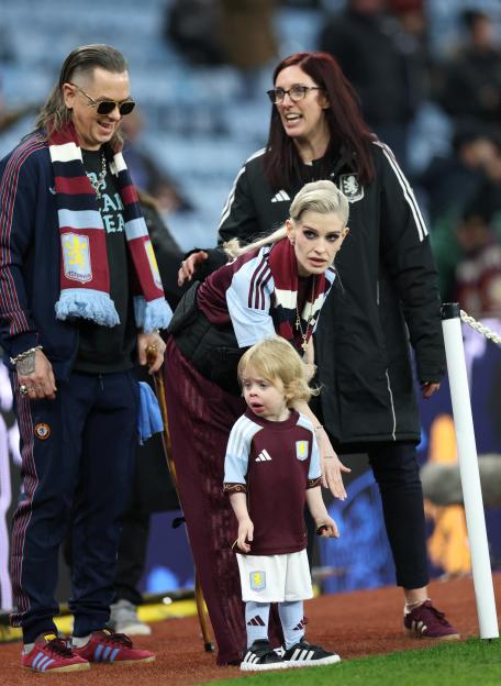 Kelly Osbourne, Sid Wilson, and their son Sidney on the sidelines at a football match.