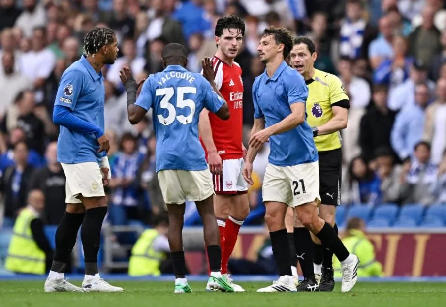 Brighton & Hove Albion and Arsenal players and a referee on the field during a Premier League match.