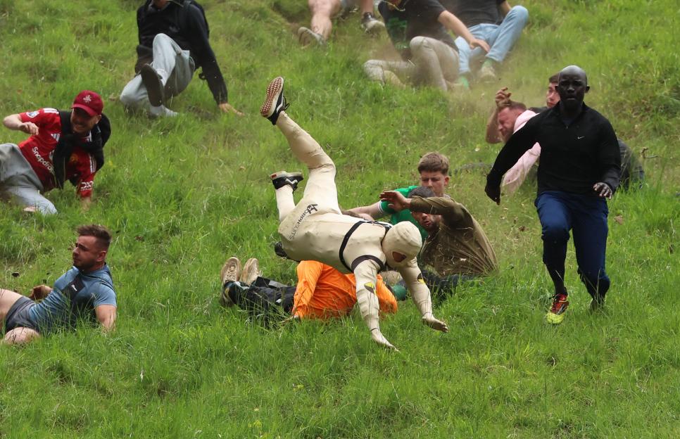 Competitors tumble down a grassy hill during the Cooper's Hill Cheese-Rolling contest.