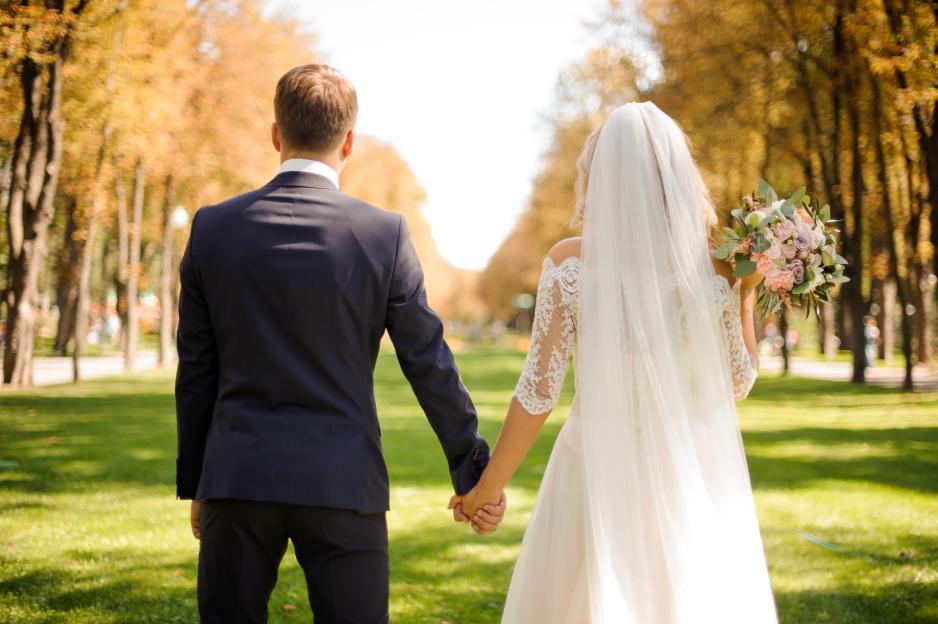 Back view of bride and bridegroom holding hands