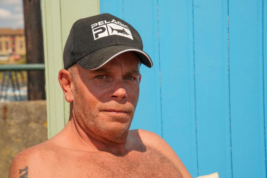 Portrait of a shirtless man wearing a Pelagic fishing hat.
