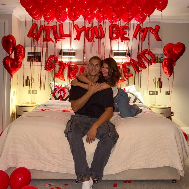 Love Island star Fitzy proposes to his girlfriend with rose petals and balloons in a hotel room.