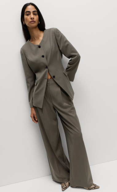 A woman models a gray pantsuit with a collarless blazer and wide-leg trousers.