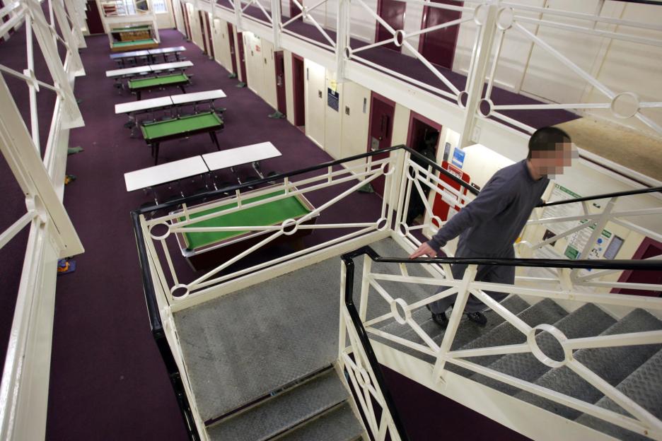 Interior of HMYOI Werrington with a person on stairs, tables, and pool tables on a purple carpet.