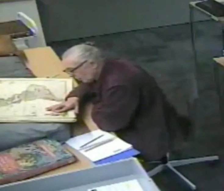 CCTV footage of Melvin West leaning over a historic map in a library or museum.