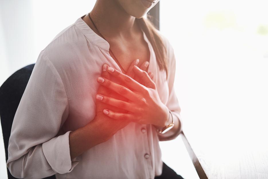 Closeup of a person holding their chest with a red overlay to signify pain.
