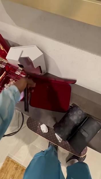 A person's hand opening a red case to reveal its contents, next to a Louis Vuitton handbag, after the Tottenham footballer Yves Bissouma's burglary.