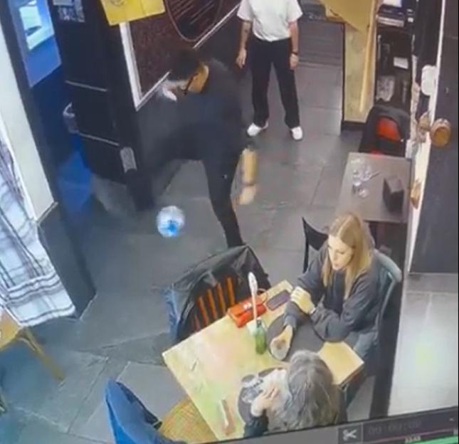 A waiter in a restaurant accidentally kicks a ball into a diner's face.