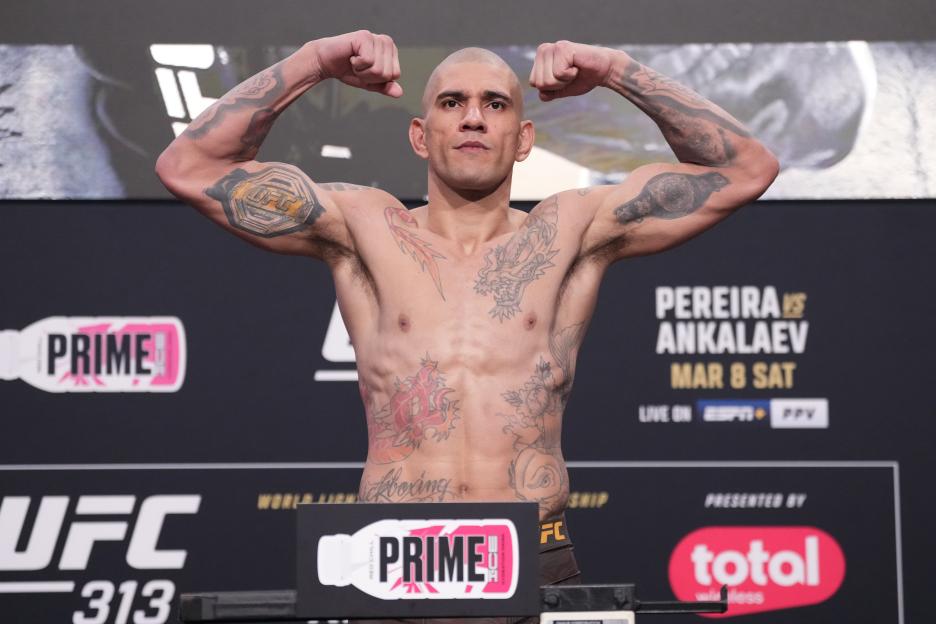Alex Pereira flexing his biceps with various tattoos on his arms and torso during the UFC 313 weigh-in.