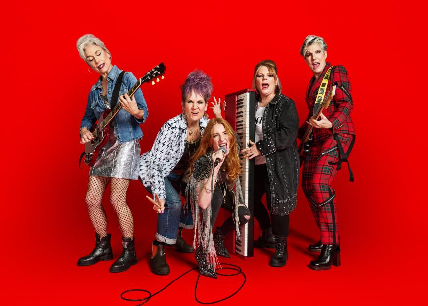 The cast of Riot Women posed as a band with musical instruments.