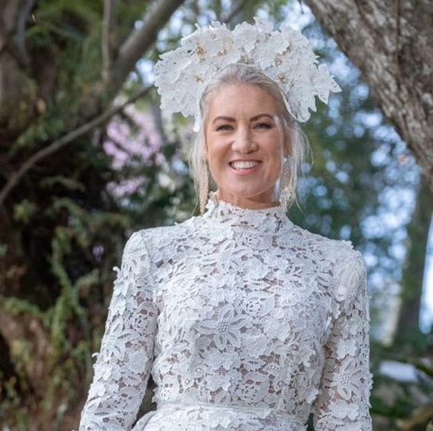 Lucinda Light in a white lace dress and floral headpiece, smiling.