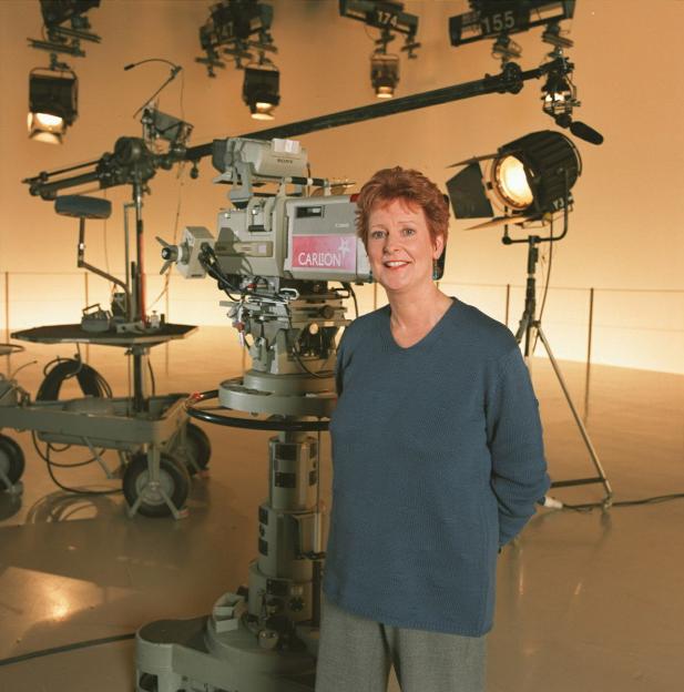 Kay Patrick, Series Producer of 'Crossroads' TV, standing in a studio with television cameras and lights.