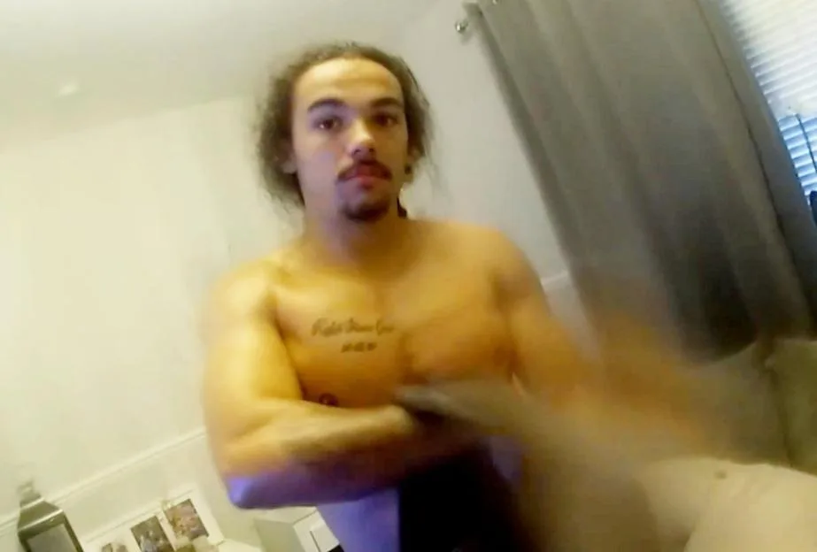 A shirtless man with long curly hair and a mustache and goatee, Ki Grant-Finlayson, is arrested by police.