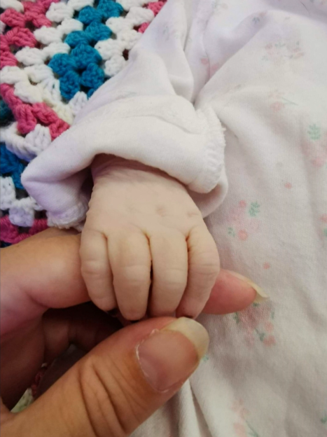 Baby Winter's hand holding Gary or Sarah's finger.