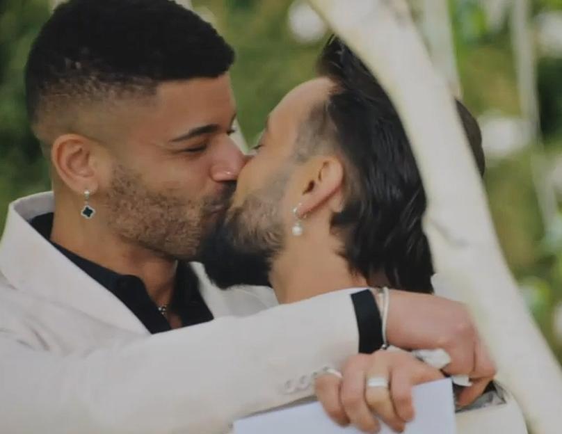 Two men in light suits kissing.