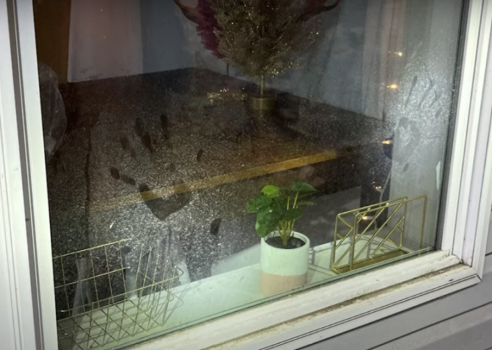 Fingerprints and smudges on a dirty window revealing the inside of a crime scene.