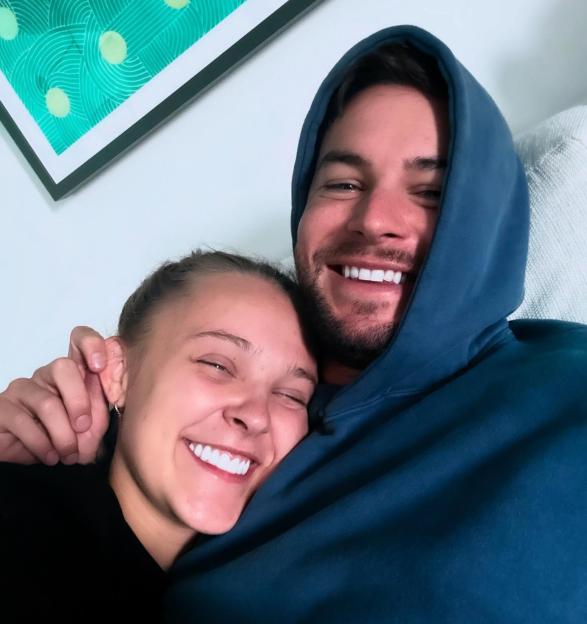 JoJo Siwa and Chris Hughes cuddling and smiling.