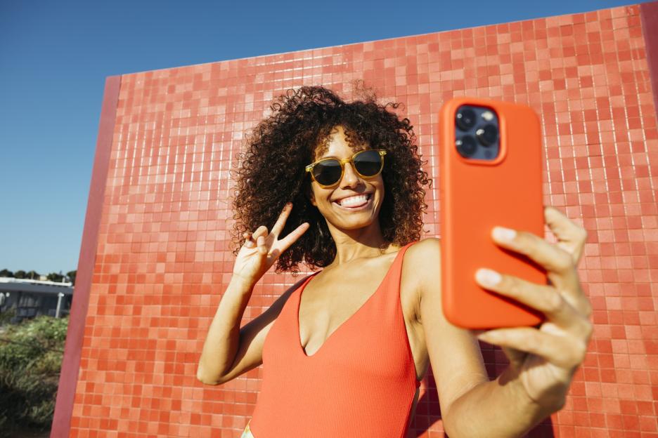 Young woman taking a selfie and making a peace sign.