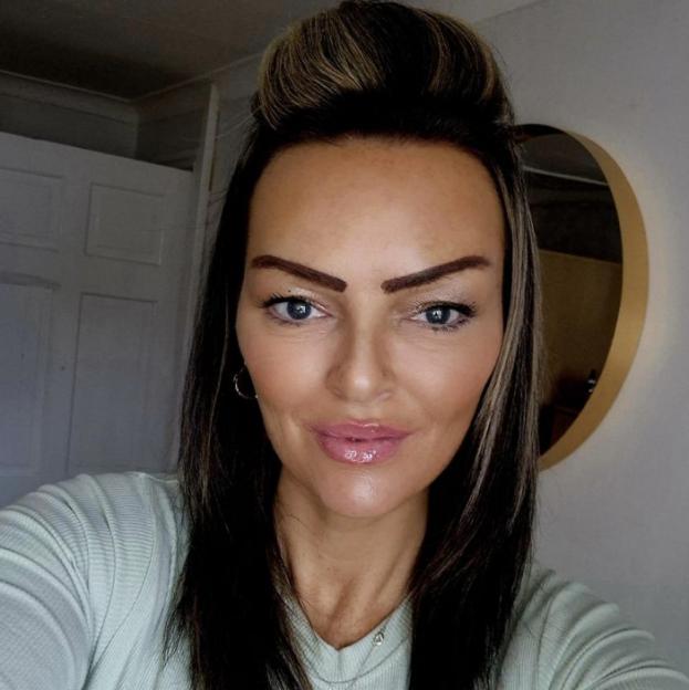 A woman with dark hair, blue eyes, and light pink lipstick looking directly at the viewer.