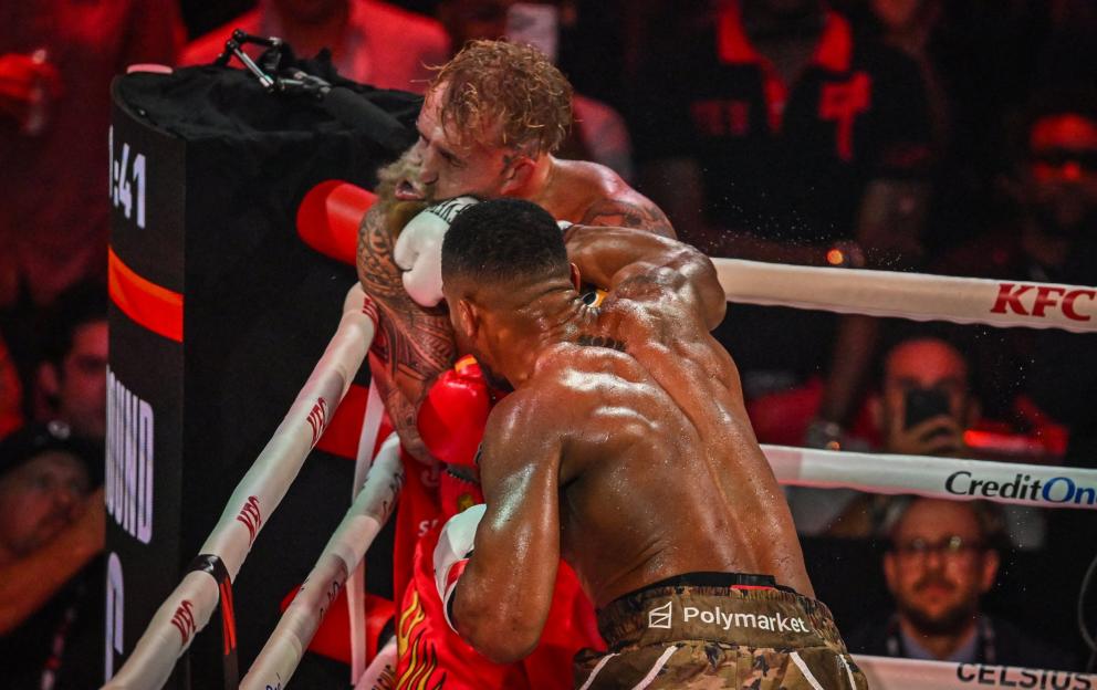 Boxers Jake Paul and Joshua battle in the ring.