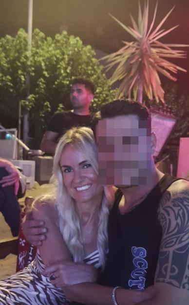 Woman with blonde hair smiling while hugging a man whose face is blurred.