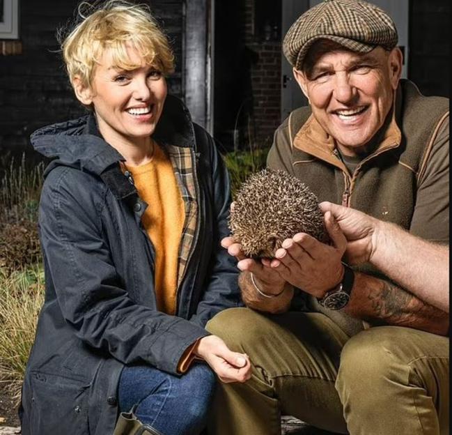 Vinnie Jones and Emma Ford holding a hedgehog in the countryside.