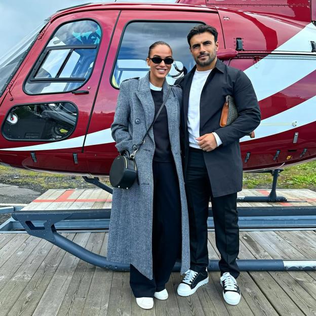 Vicki Pattison and her partner standing in front of a helicopter.