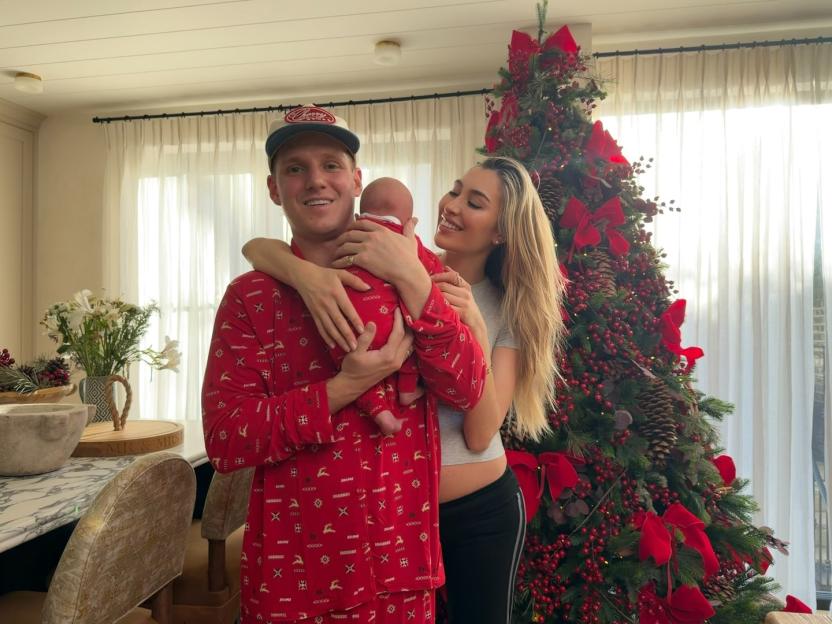 Jamie Laing, Sophie Habboo, and baby Ziggy pose in front of a Christmas tree.