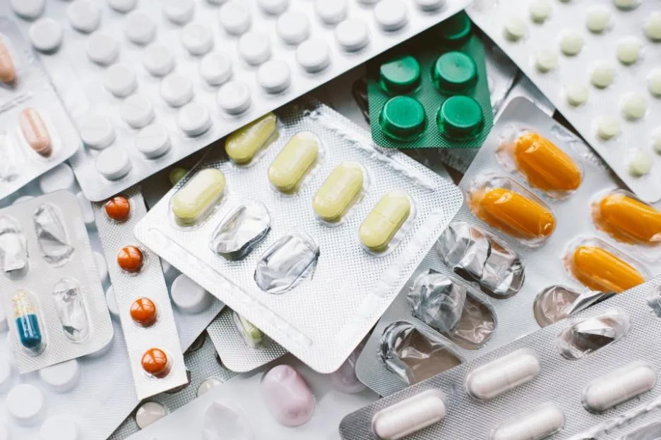 Numerous colorful medication pills and capsules in various blister packs.