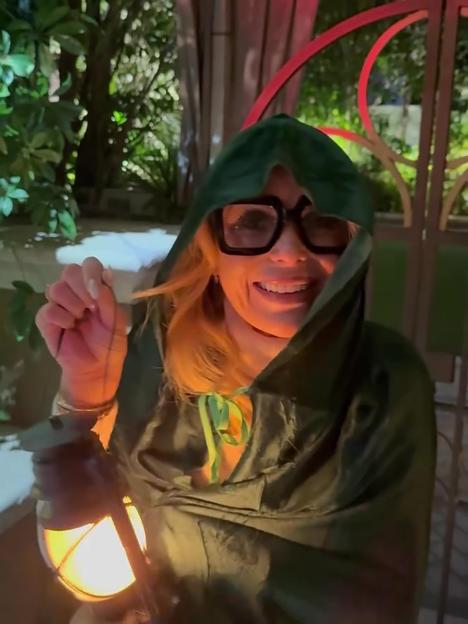Amanda Holden dressed in a green hooded robe and holding a lantern for Halloween.