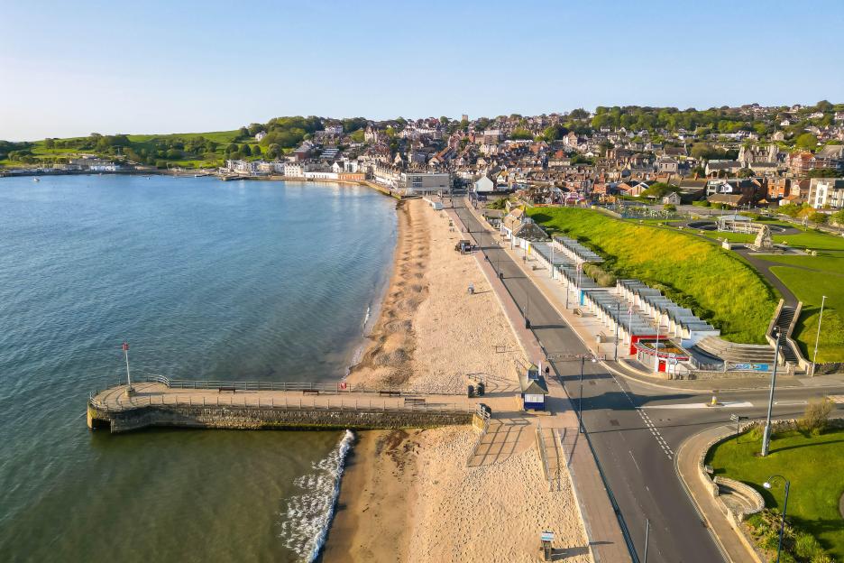 Aerial view of Swanage, Dorset, showing the beach, pier, and town extending up a hillside.
