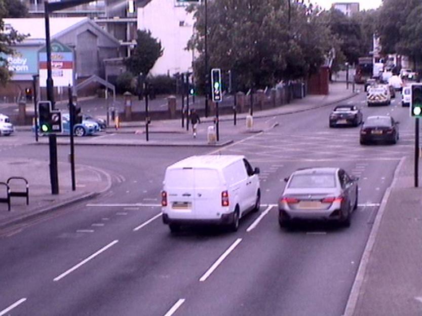 CCTV footage of vehicles on a street, including a white van and a silver car.