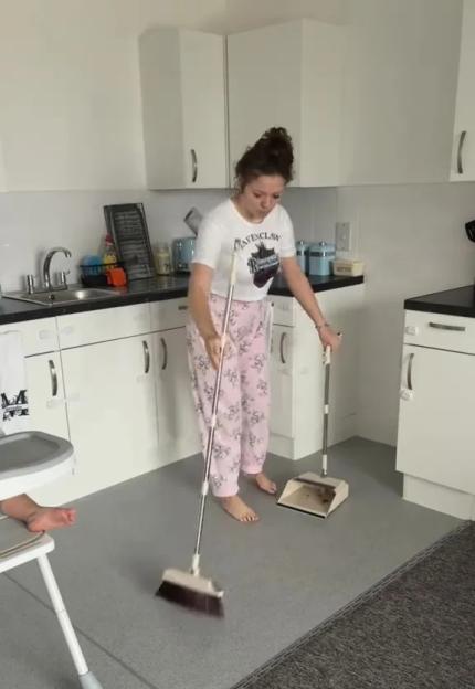A woman in black holding a refrigerator door open, with a child in a high chair nearby and a blue tent in the background.