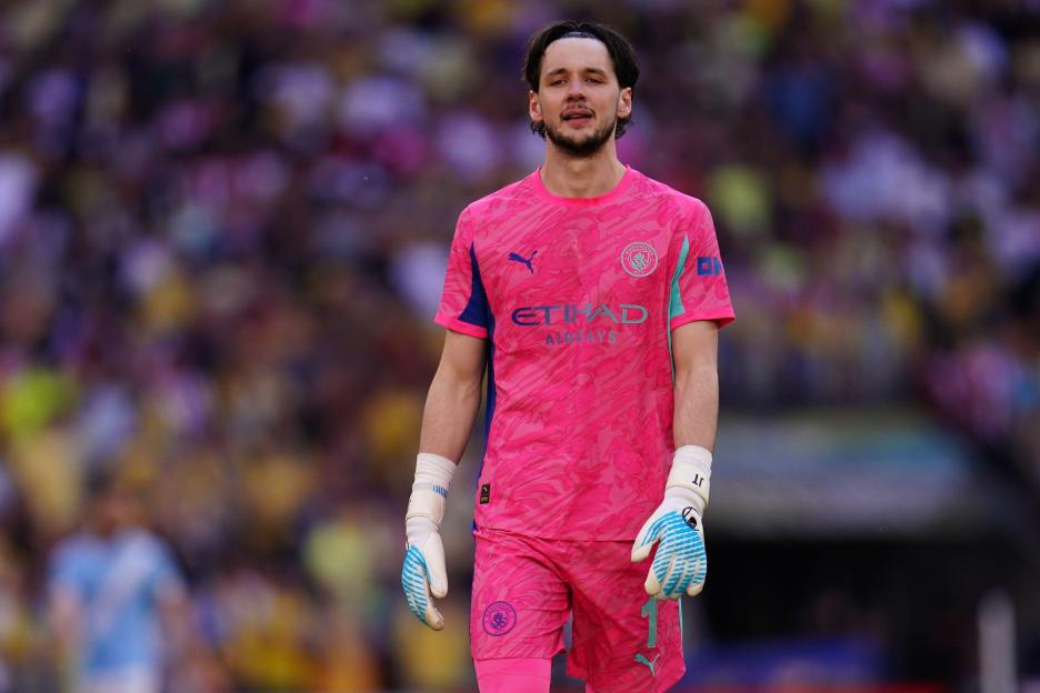 Manchester City goalkeeper James Trafford in a pink and blue uniform.