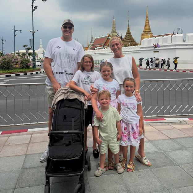 The Fury family, including Tyson and Paris, pose with their children and a stroller in front of a Thai temple.