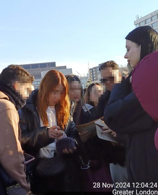 People gathered at an outdoor market, looking at items.