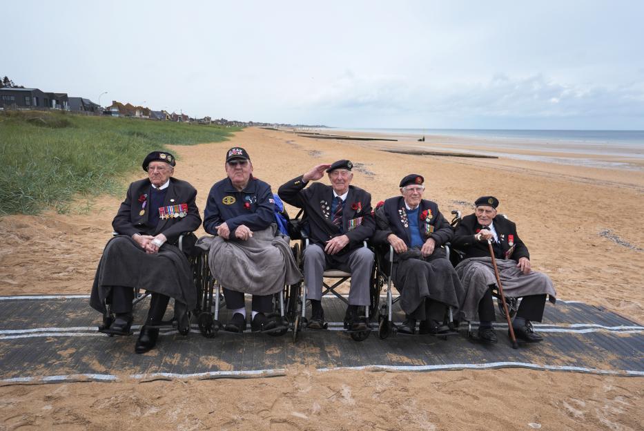 Five D-Day veterans, Ken Hay, Richard Aldred, Henry Rice, Jim Grant and John Dennet, seated in wheelchairs on Sword Beach.