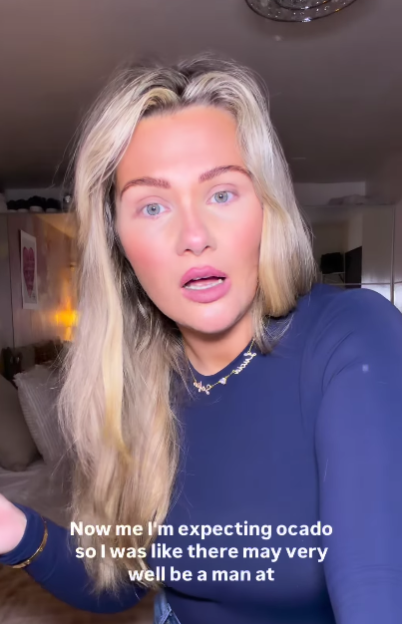 Shaughna Phillips, a woman with long blonde hair, wearing a navy blue top and a necklace, speaks in a video.