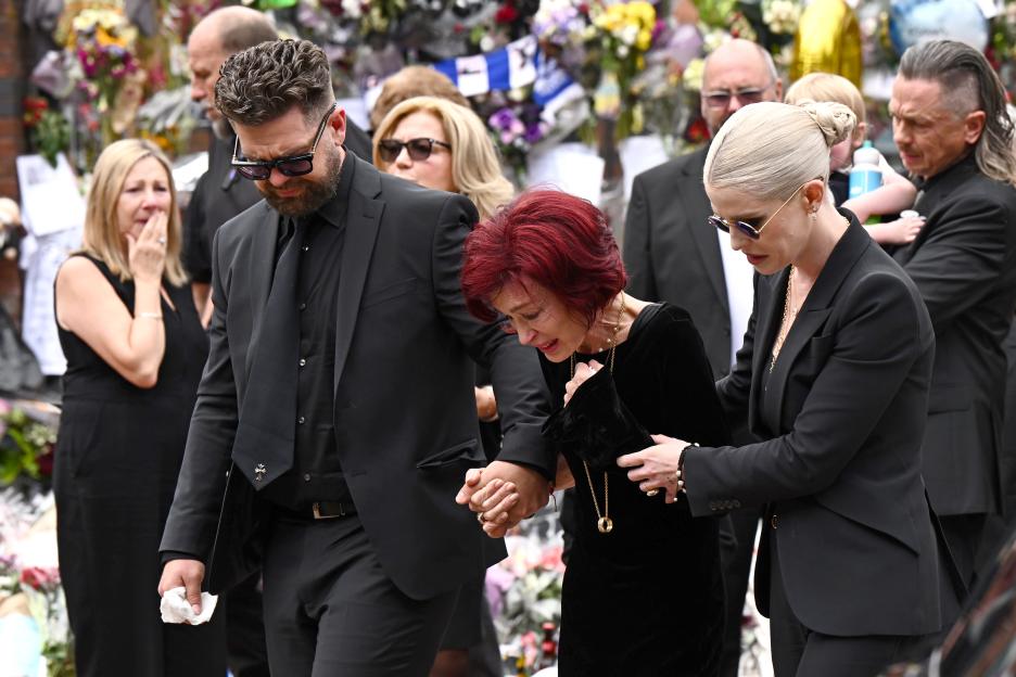 Jack, Sharon, and Kelly Osbourne walking through Birmingham, with flowers in the background.