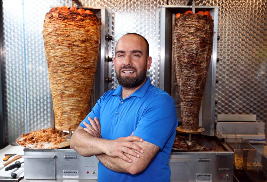 Soran Mahmoud from Habibi restaurant in Burngreave stands in front of two shawarma rotisseries.