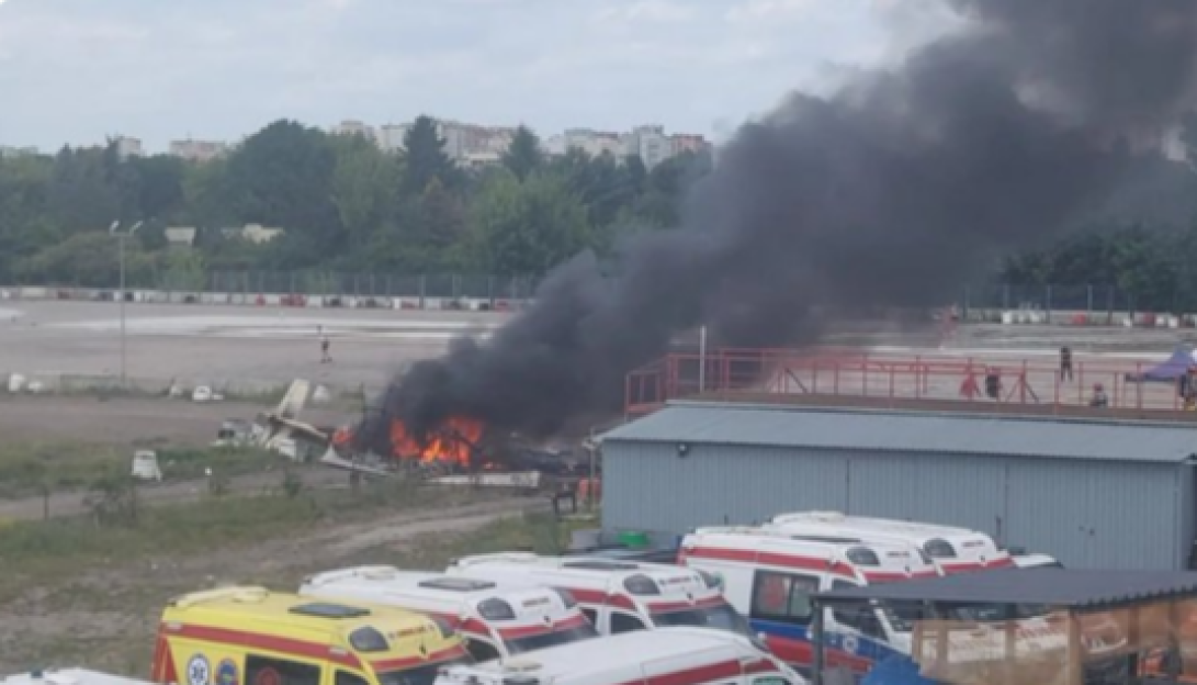 Small plane crash in Warsaw's Bemowo, with wreckage burning and emergency vehicles nearby.