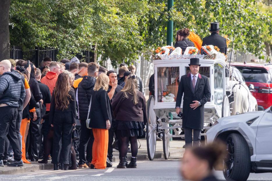 A funeral procession for Jacob Matusiak arriving at St John's Church, Middlesbrough, with a hearse and mourners.
