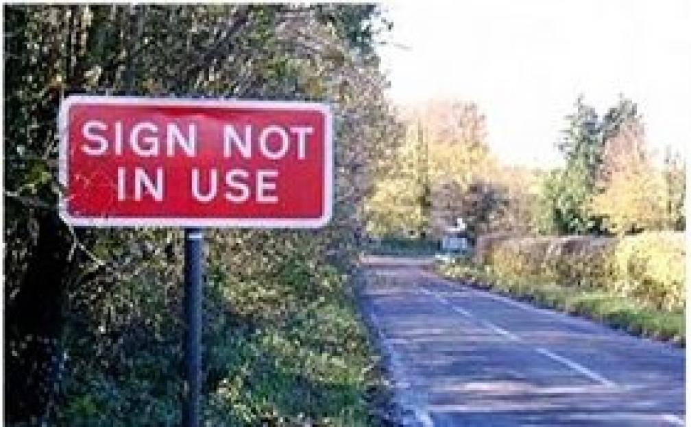 A red sign on the side of a road that says "SIGN NOT IN USE".