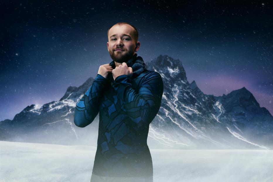 Man in blue activewear in a snowy mountain landscape.