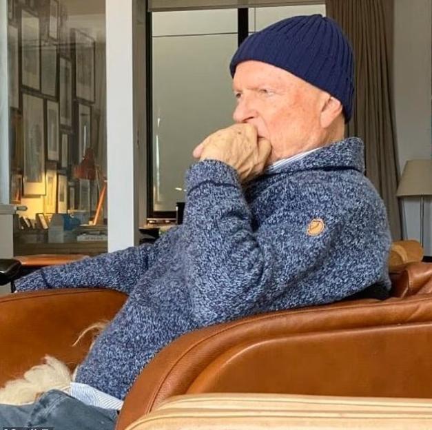 Man wearing a blue beanie and sweater, seated in a brown leather chair.