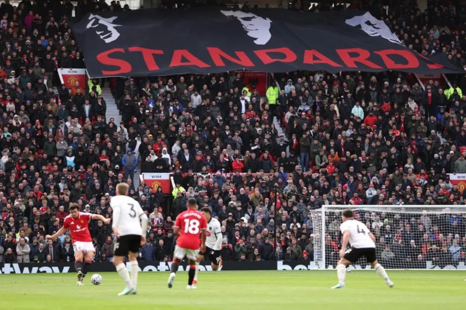 Manchester United fans hold up a banner reading 'Standards' with the faces of club legends Eric Cantona, Roy Keane and Bryan Robson during a match at Old Trafford.