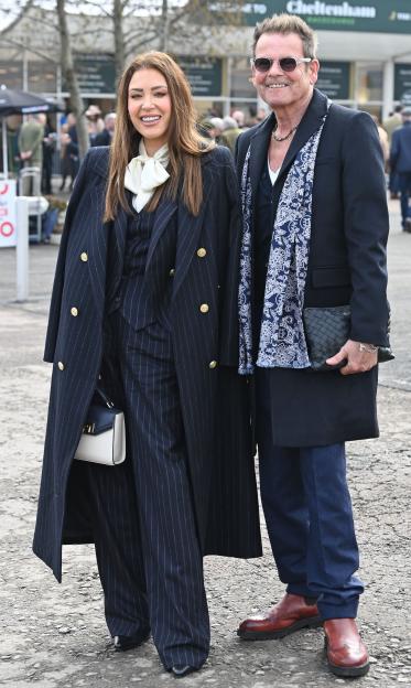 Two guests, a woman and a man, attend Gold Cup Day at Cheltenham Racecourse.