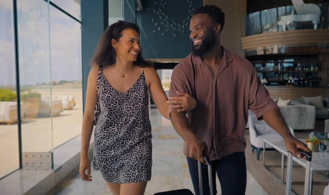 Katisha Atkinson and Javen Palmer smiling, walking arm-in-arm through a hotel lobby.
