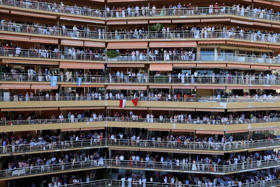Fans watch the F1 Grand Prix of Monaco from balconies on a building.