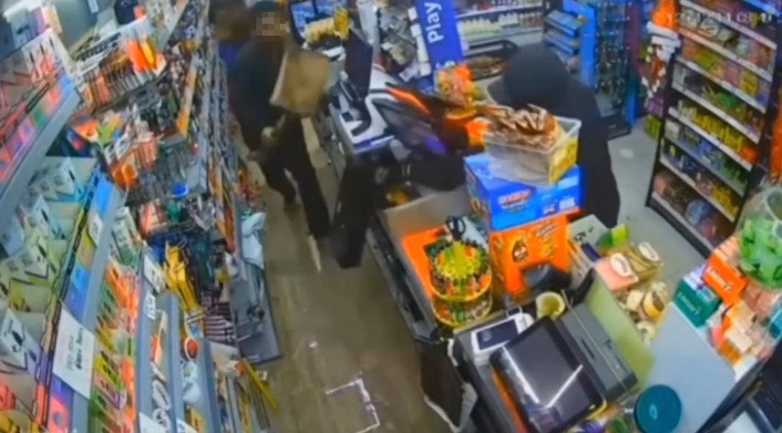 Still from surveillance footage showing a shopkeeper confronting a hooded thief.